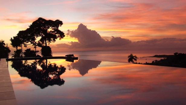 Sonnenuntergang über dem Meer, gesehen von einem Infinity-Pool aus.
