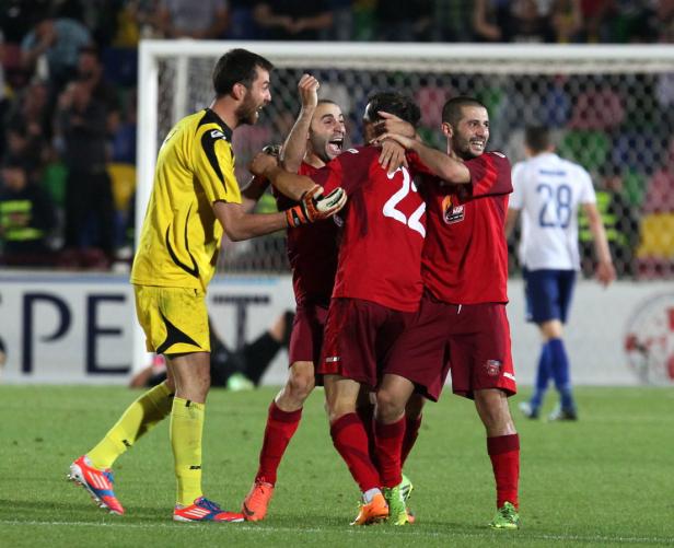 Fußballspieler umarmen sich auf dem Spielfeld und feiern ein Tor.
