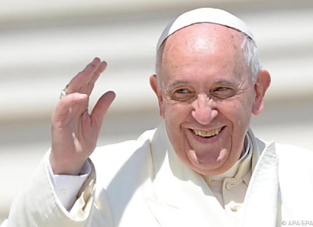 Papst Franziskus lächelt und winkt.