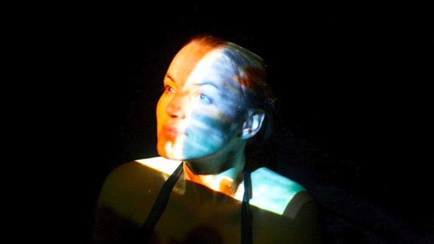 Das Gesicht einer Frau ist mit farbigem Licht beleuchtet.