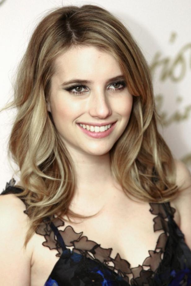 Emma Roberts lächelt in einem schwarzen Kleid mit Blumenmuster.