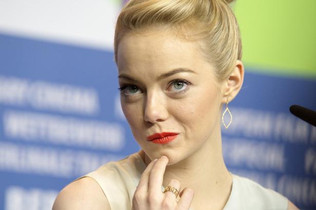 Emma Stone bei einer Pressekonferenz, den Finger ans Kinn gelegt.