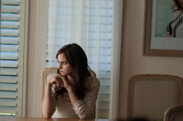 Emma Watson sitzt an einem Tisch und schaut nachdenklich aus dem Fenster.