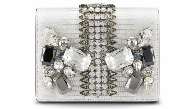 Eine weiße Clutch mit Reptilienmuster und aufwendiger Schmucksteinapplikation.