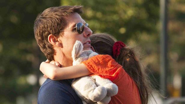Tom Cruise umarmt ein Kind, das ein Stofftier hält.