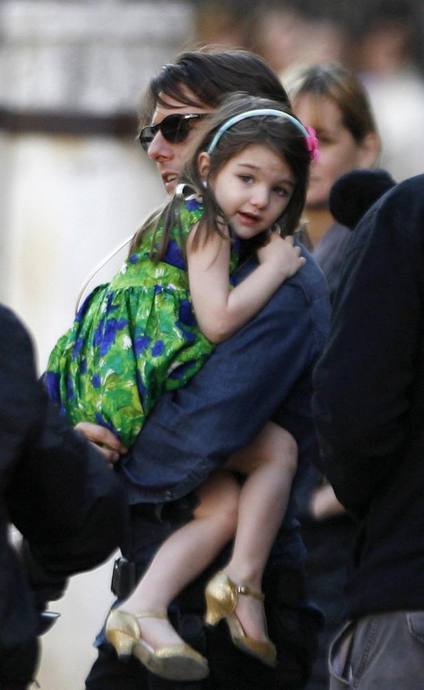 Tom Cruise trägt seine Tochter Suri in einem grünen Kleid und goldenen Schuhen.