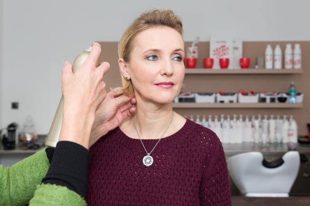Eine Frau bekommt im Friseursalon die Haare mit Haarspray fixiert.