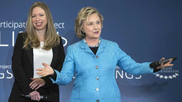 Hillary Clinton spricht mit einem Mikrofon in der Hand, während Chelsea Clinton daneben steht.