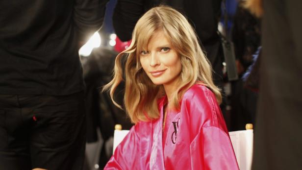 Ein blondes Model trägt einen pinkfarbenen Bademantel mit dem Victoria's Secret-Logo.