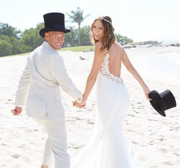 Ein frisch vermähltes Paar in Hochzeitskleidung geht am Strand entlang.