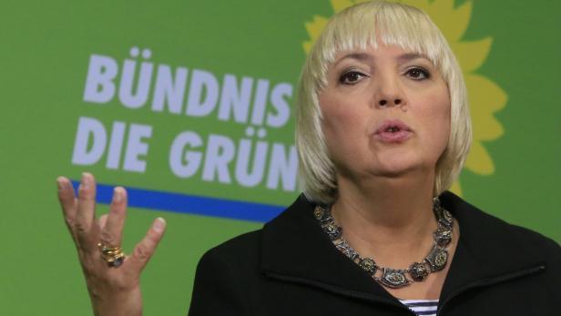 Eine Frau spricht vor einem Hintergrund mit dem Logo von Bündnis 90/Die Grünen.