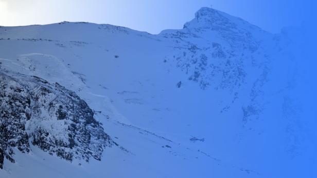 Ein Hubschrauber landet in einer verschneiten Berglandschaft.