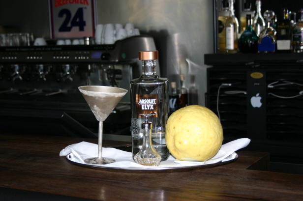 Eine Flasche Absolut Elyx Wodka, ein Martiniglas und eine Zitrone auf einem Tablett.