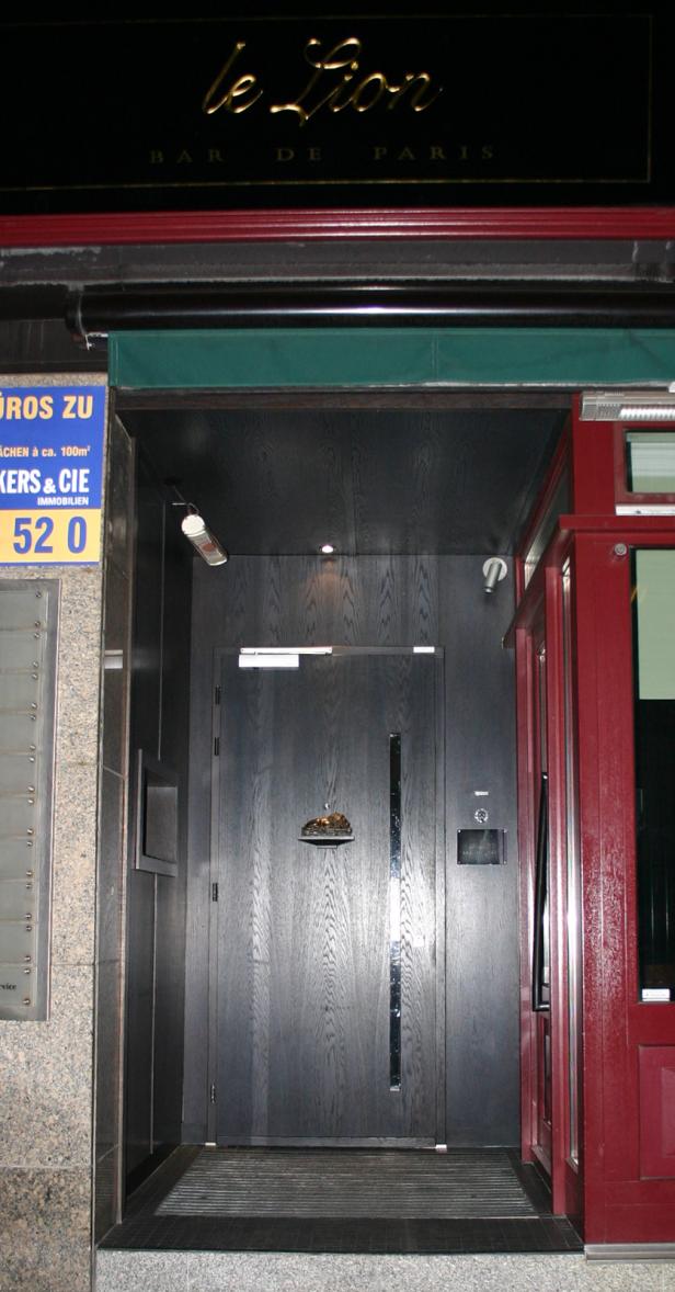 Der Eingang zur „Le Lion Bar de Paris“ mit einer dunklen Holztür.