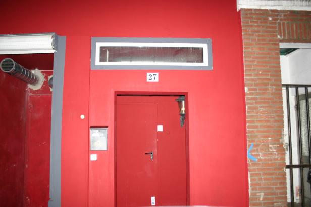 Eine rote Fassade mit der Hausnummer 27 über der Tür.