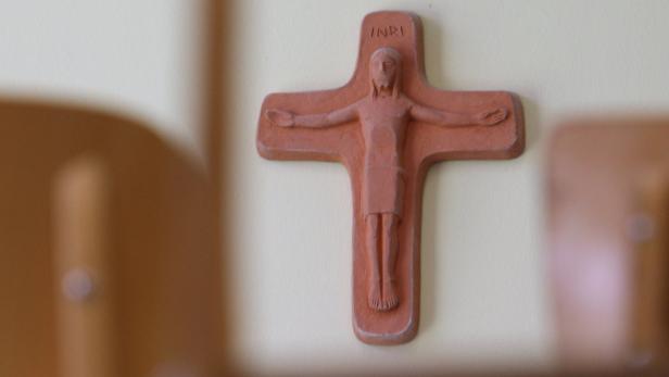 Ein Terrakotta-Kruzifix hängt an einer Wand.
