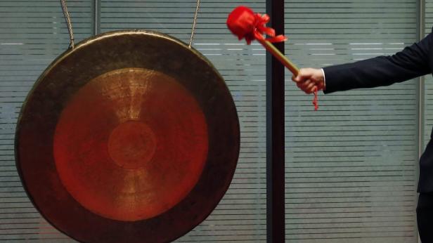 Eine Person im Anzug schlägt mit einem Schlägel auf einen Gong.