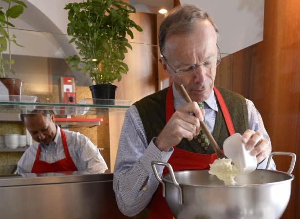 Ein Mann mit Brille rührt eine Creme in einer großen Schüssel um.