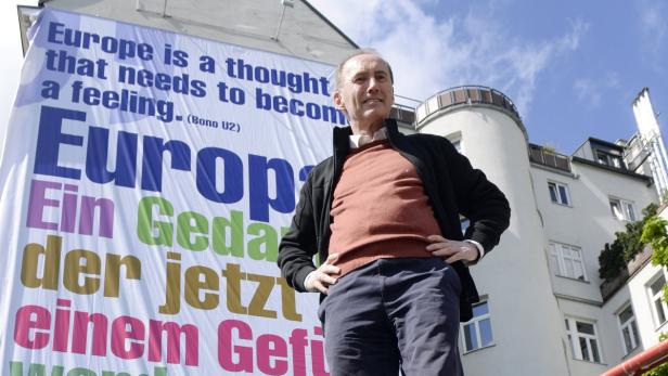 Ein Mann steht vor einem Gebäude mit einem Banner, das ein Zitat von Bono (U2) über Europa zeigt.