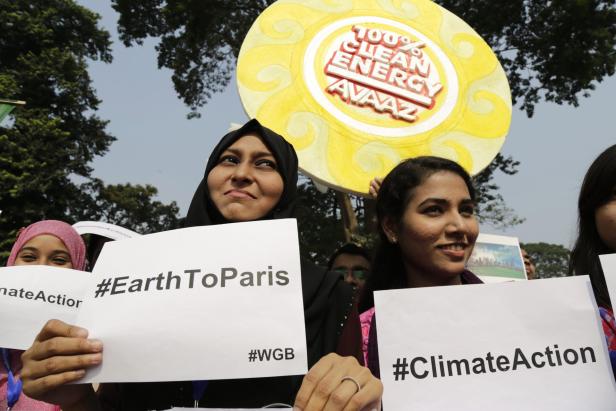 Frauen demonstrieren mit Schildern für Klimaschutz und saubere Energie.