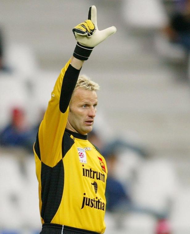 Ein Torwart in gelb-schwarzer Uniform hebt die Hand mit einem Torwarthandschuh.