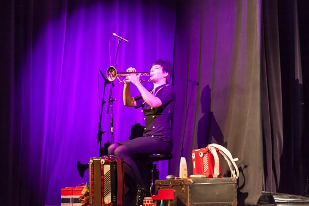 Eine Frau in Uniform sitzt auf einer Bühne und spielt Trompete.