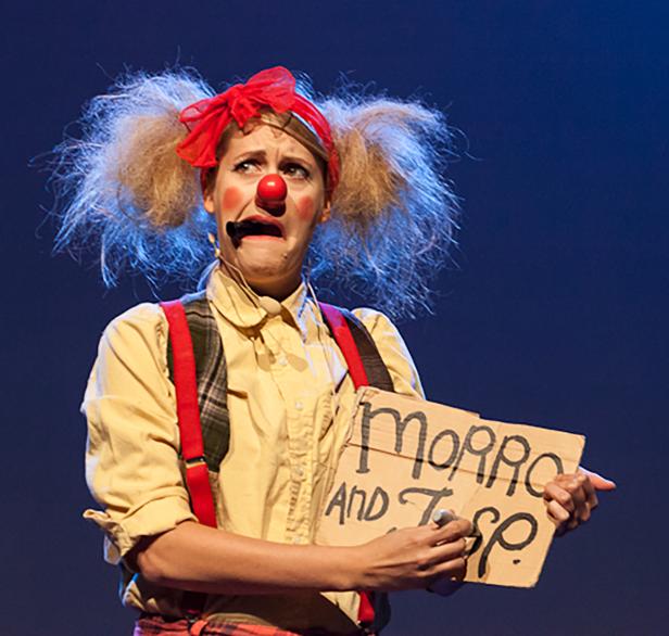 Eine traurige Clownin hält ein Schild mit der Aufschrift „Morro and TSp“.