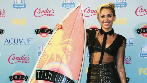 Miley Cyrus posiert mit einem Surfbrett bei den Teen Choice Awards 2013.