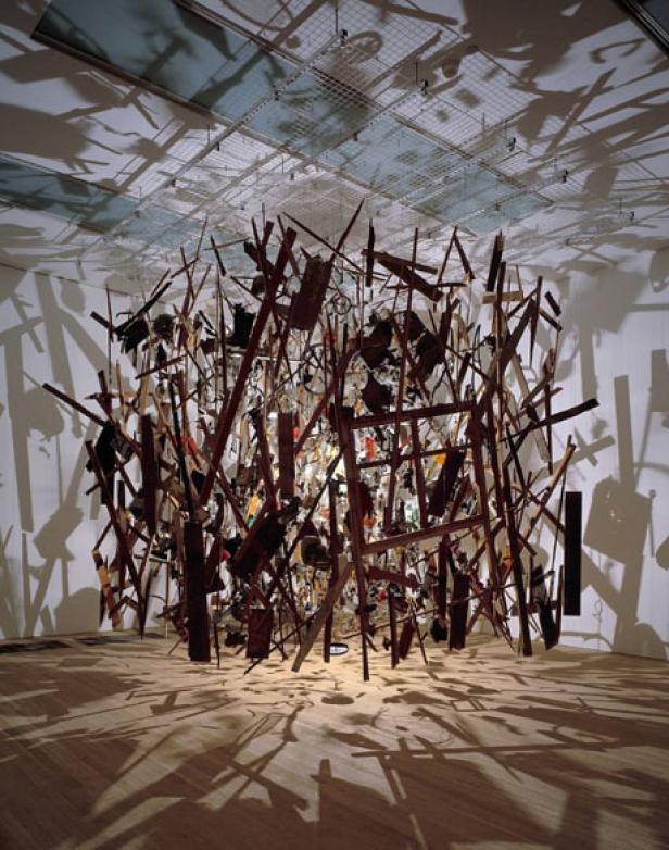 Eine raumfüllende Installation aus Holzstücken und anderen Materialien hängt von der Decke.