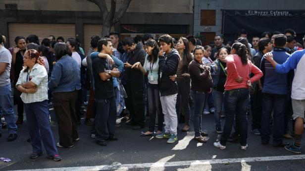 Eine Menschenmenge steht auf einer Straße vor einem Gebäude.