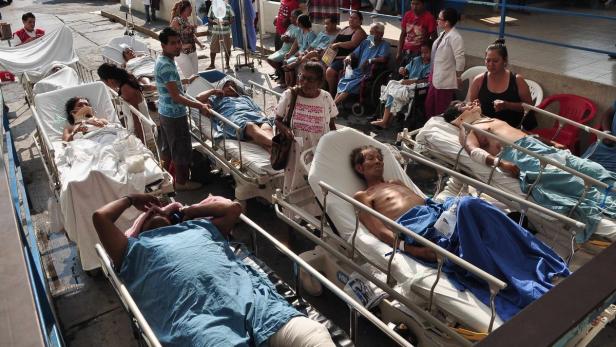 Viele Patienten liegen im Freien auf Krankenhausbetten und werden behandelt.