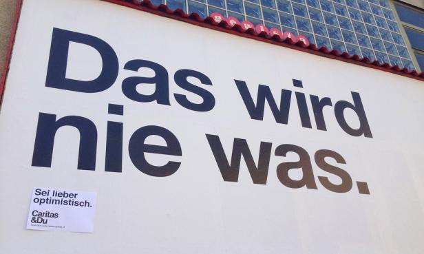 Auf einer Wand steht der Spruch „Das wird nie was.“ und „Sei lieber optimistisch.“.