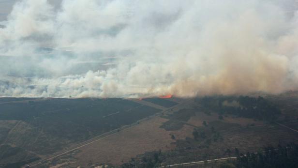 Ein Waldbrand erzeugt dichten Rauch, der über das Land zieht.