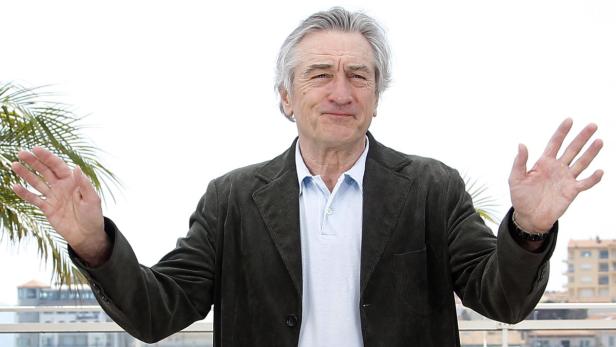 Robert De Niro posiert mit ausgestreckten Armen.