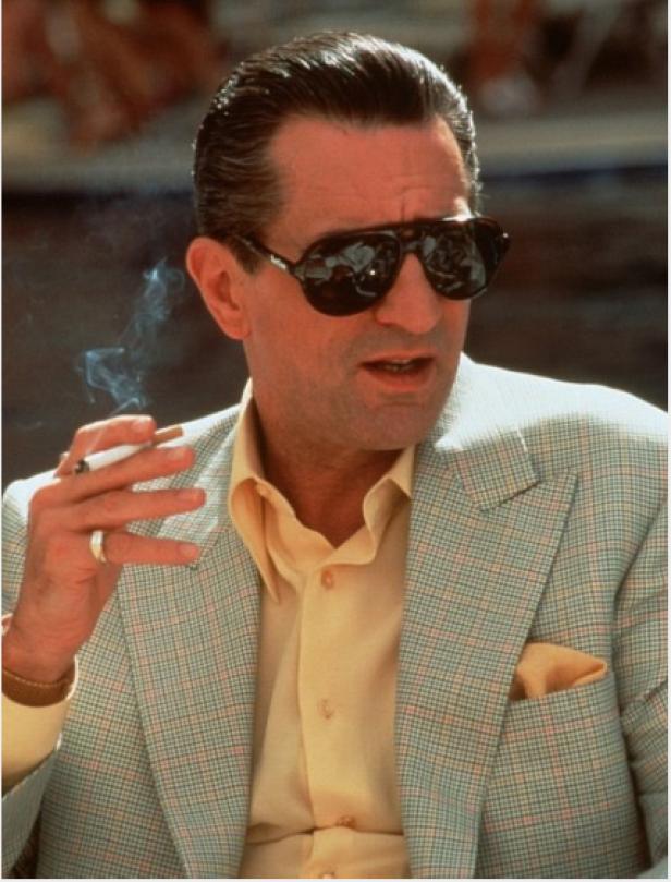 Robert De Niro mit Sonnenbrille und Zigarette in einem hellen Anzug.