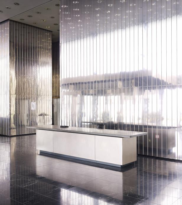 Ein Empfangstresen steht in einem modernen Gebäude mit verspiegelten Wänden.
