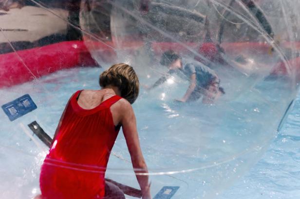 Zwei Personen befinden sich in einer großen, transparenten Kugel auf dem Wasser.