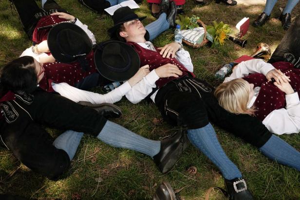 Eine Gruppe von Personen in Tracht liegt entspannt auf einer Wiese.