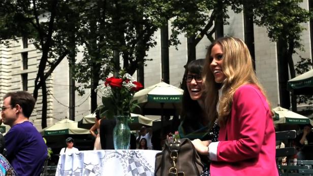 Zwei lachende Frauen stehen im Bryant Park in New York.