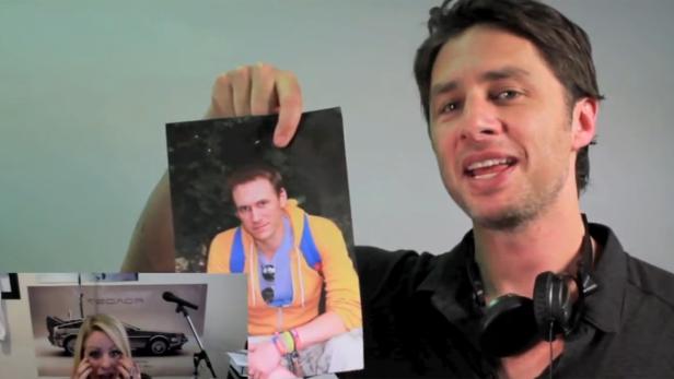 Zach Braff hält ein Foto von einem Mann mit gelbem Pullover hoch.