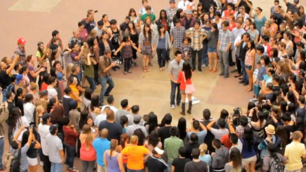 Ein Paar steht im Kreis einer Menschenmenge, die Fotos macht.