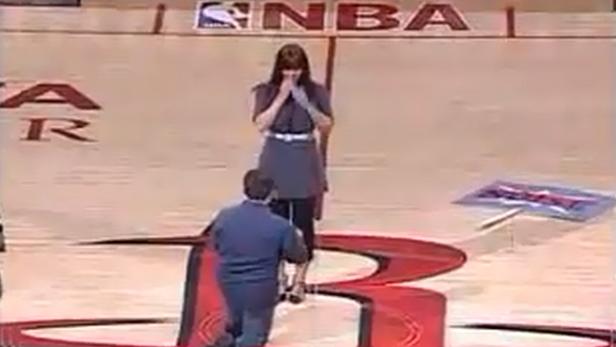 Ein Mann macht einer Frau auf dem Spielfeld der NBA einen Heiratsantrag.