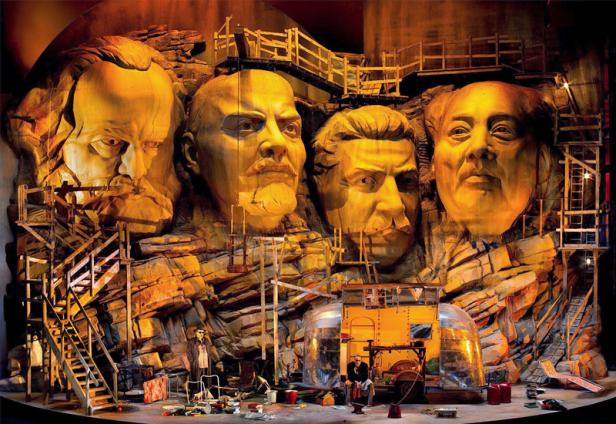 Eine Bühnenkulisse zeigt die in Stein gehauenen Köpfe von Marx, Lenin, Stalin und Mao.