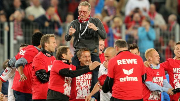 Fußballtrainer wird von seinen Spielern auf den Schultern getragen und gefeiert.