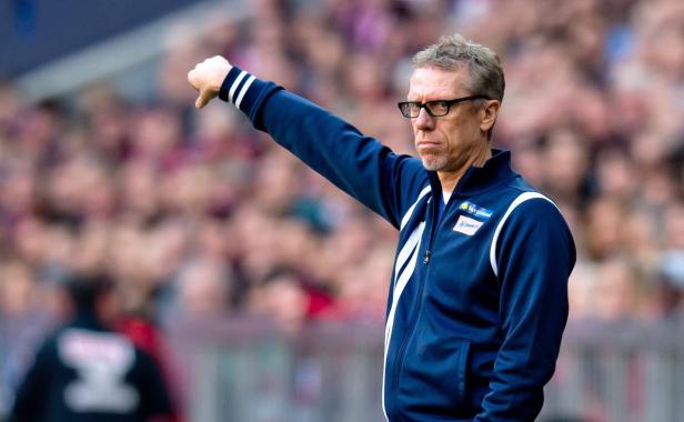 Ein Trainer mit Brille gestikuliert vor einer Zuschauermenge.