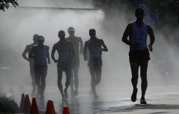 Mehrere Marathonläufer laufen durch einen Nebel auf der Straße.