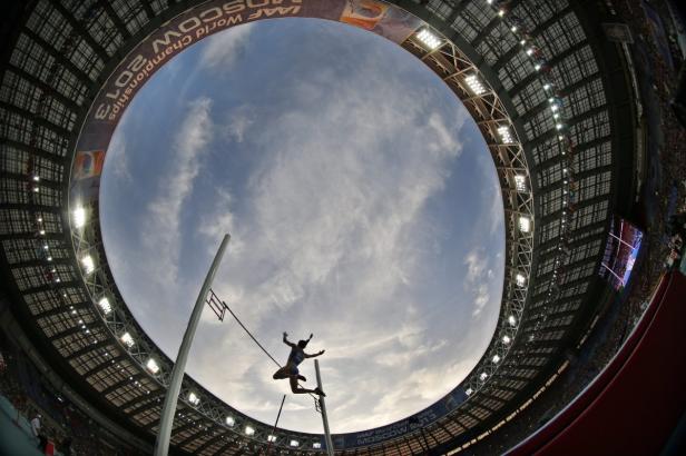 Ein Stabhochspringer während eines Wettkampfs in einem Stadion.