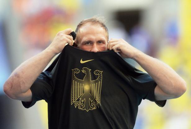 Ein Mann hält ein schwarzes T-Shirt mit dem deutschen Bundesadler vor sein Gesicht.