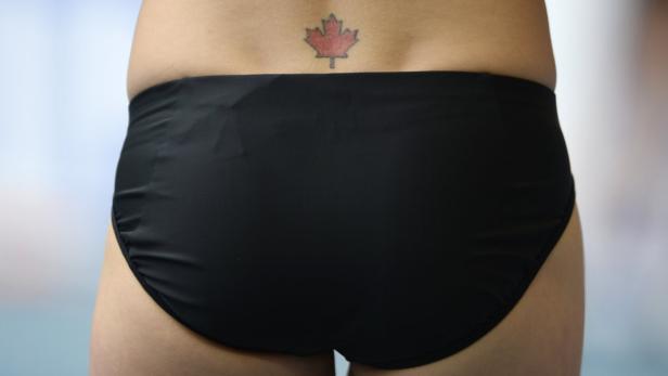 Eine Person mit schwarzer Badehose und einem Tattoo einer roten Ahornblatt auf dem Rücken.