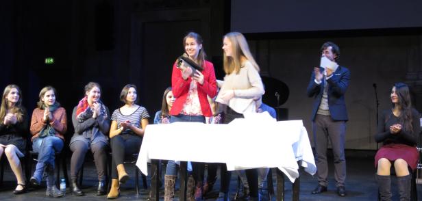 Eine junge Frau erhält auf einer Bühne eine Auszeichnung.